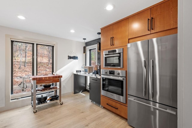 kitchen featuring pendant lighting, light hardwood / wood-style flooring, and stainless steel refrigerator