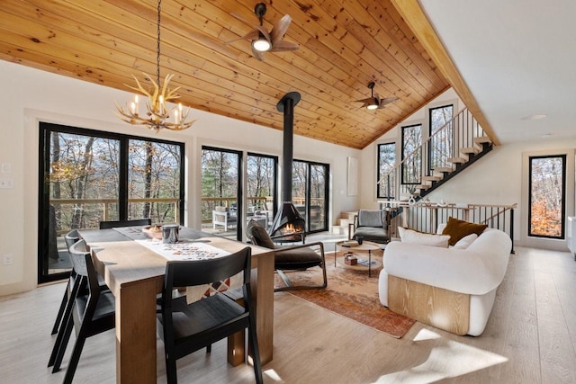 dining space with beamed ceiling, light hardwood / wood-style floors, ceiling fan with notable chandelier, and a healthy amount of sunlight