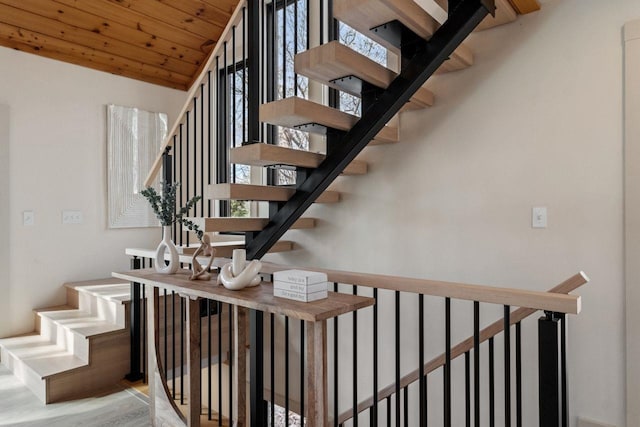 staircase featuring hardwood / wood-style flooring, wooden ceiling, and a high ceiling