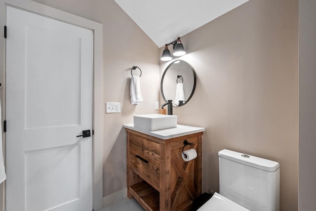 bathroom featuring vanity, toilet, and lofted ceiling