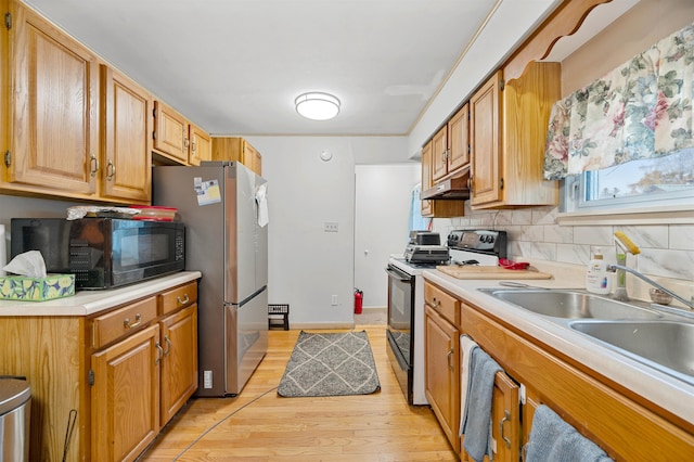 kitchen featuring stainless steel fridge, sink, decorative backsplash, light hardwood / wood-style floors, and electric range