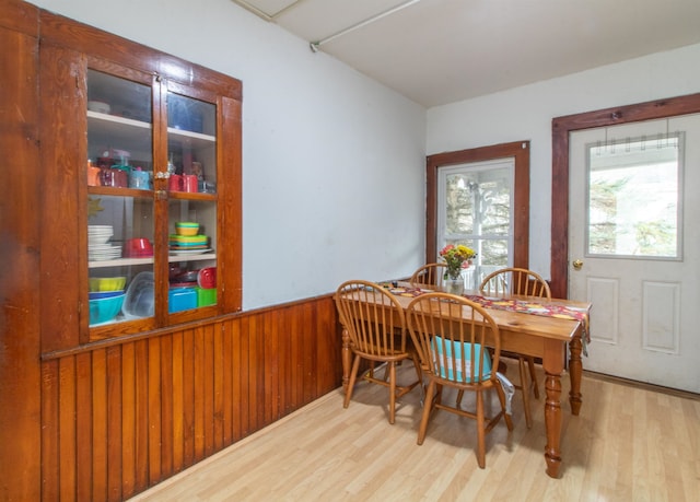 dining room featuring light wood-type flooring and wood walls