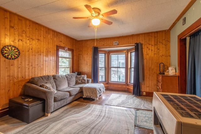 living room featuring hardwood / wood-style flooring, ceiling fan, and wooden walls