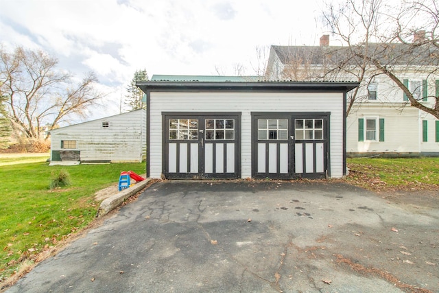 exterior space with a garage, an outdoor structure, and a lawn