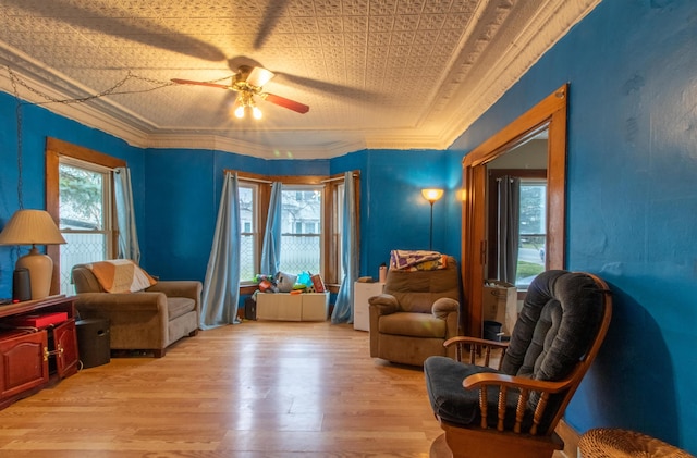 living area featuring light hardwood / wood-style flooring, ceiling fan, and crown molding