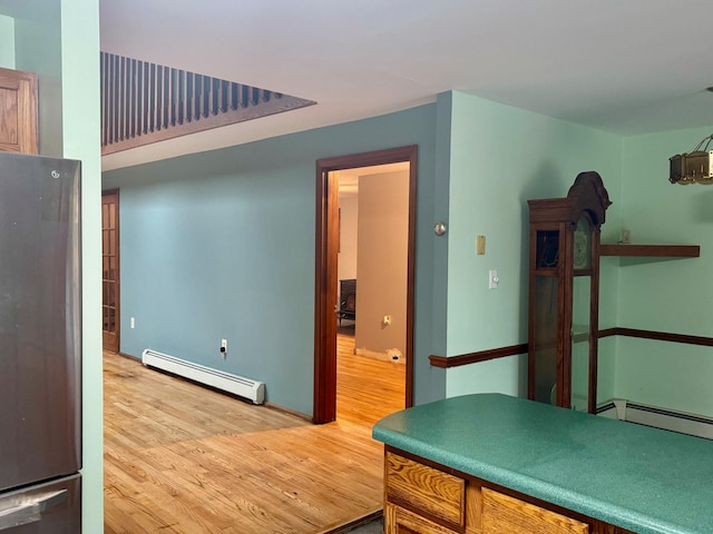 kitchen with stainless steel refrigerator, baseboard heating, and wood-type flooring