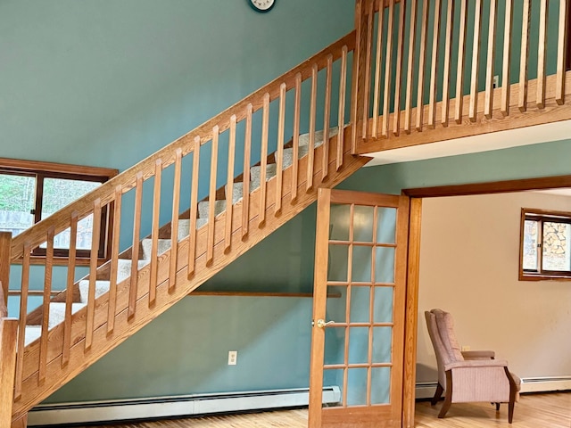 stairs featuring baseboard heating, hardwood / wood-style floors, and plenty of natural light