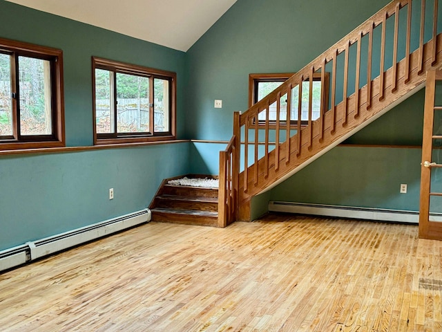 stairway featuring baseboard heating, wood-type flooring, and lofted ceiling