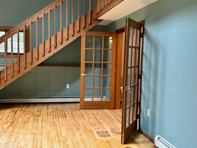 interior space with baseboard heating, french doors, and hardwood / wood-style flooring