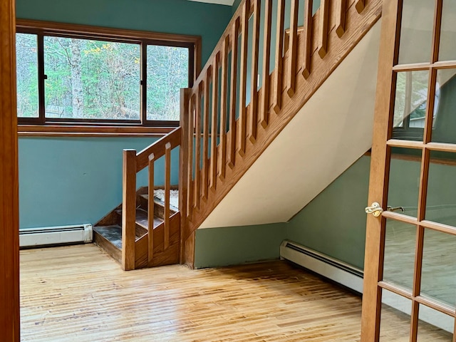 staircase with a baseboard heating unit and hardwood / wood-style flooring