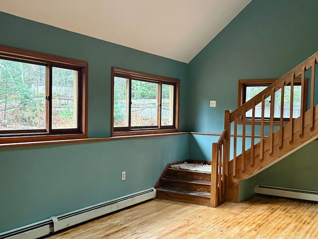 stairs featuring a wealth of natural light, wood-type flooring, and a baseboard radiator