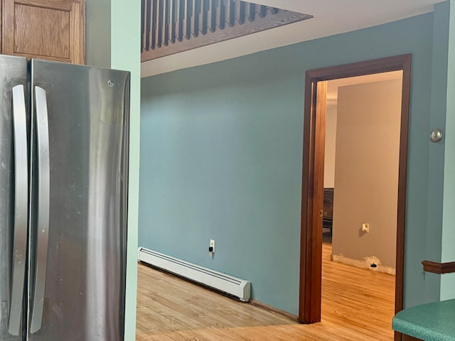 interior space featuring light hardwood / wood-style floors, baseboard heating, and stainless steel fridge