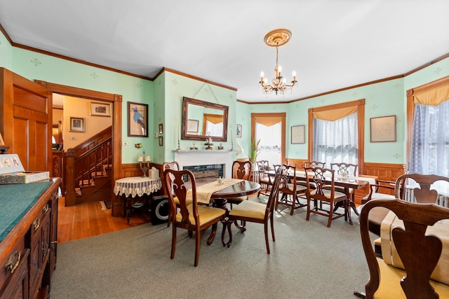 carpeted dining area with wood walls, a chandelier, and ornamental molding