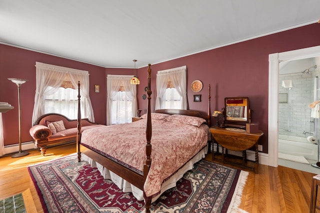 bedroom featuring hardwood / wood-style floors, ornamental molding, and ensuite bath