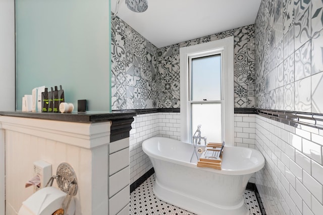 bathroom with tile patterned flooring, a bathing tub, and tile walls