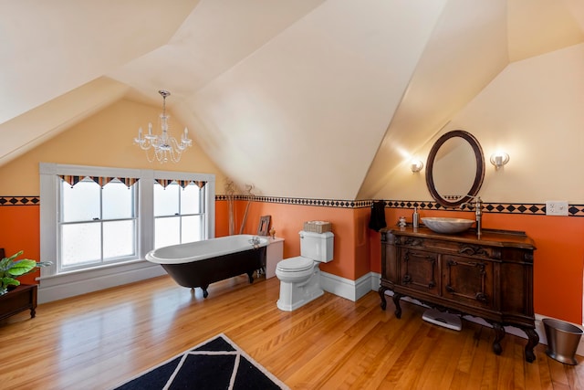 bathroom with hardwood / wood-style floors, a notable chandelier, toilet, and vaulted ceiling