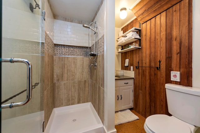 bathroom featuring toilet, vanity, and a shower with shower door