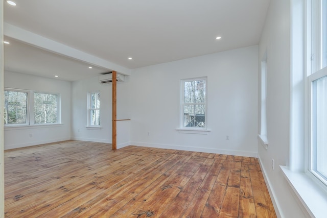 empty room with a wall mounted AC and light hardwood / wood-style floors