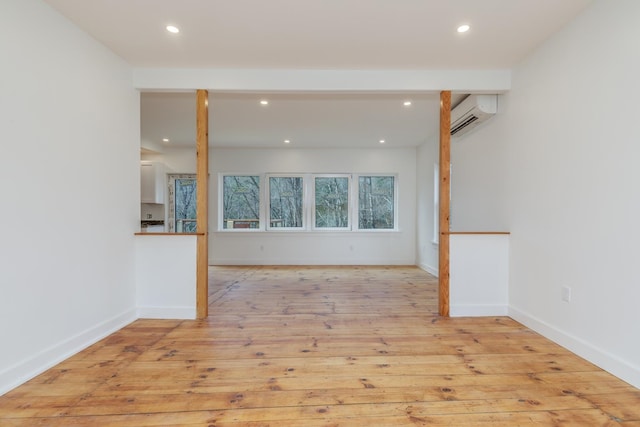 spare room featuring an AC wall unit and light hardwood / wood-style flooring