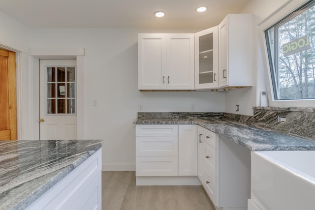 kitchen featuring white cabinets, light hardwood / wood-style floors, and dark stone countertops