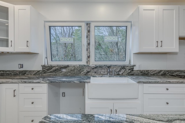 kitchen featuring dark stone counters, sink, and white cabinets