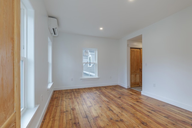 empty room featuring light wood-type flooring and a wall mounted air conditioner