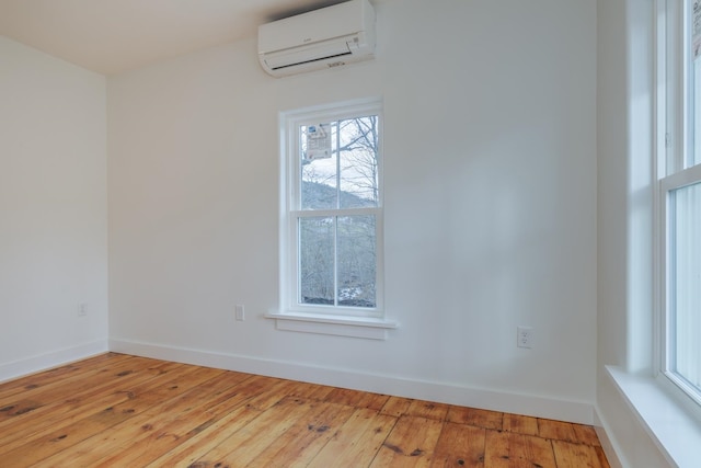 empty room featuring a wall unit AC and light wood-type flooring