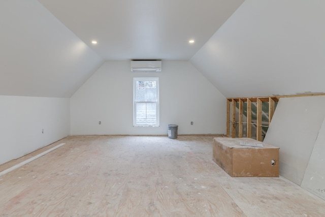 additional living space featuring vaulted ceiling, a wall mounted air conditioner, and light hardwood / wood-style floors