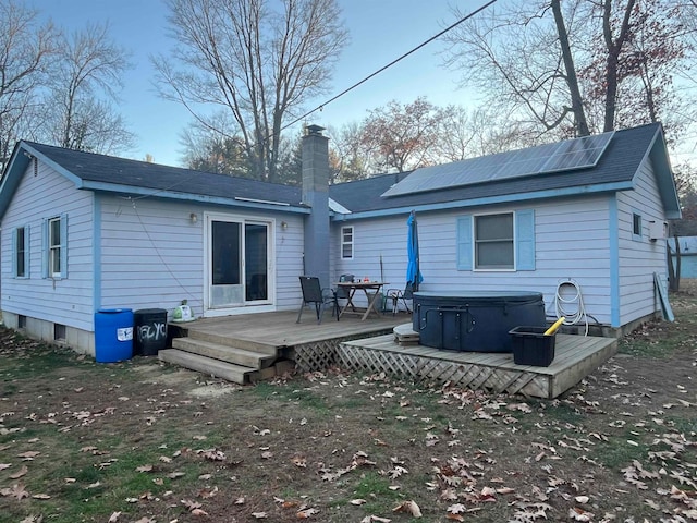 rear view of house featuring solar panels, a deck, and a hot tub