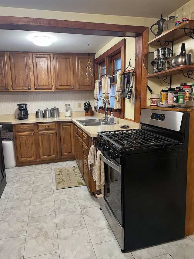 kitchen featuring decorative backsplash, sink, decorative light fixtures, and stainless steel gas range