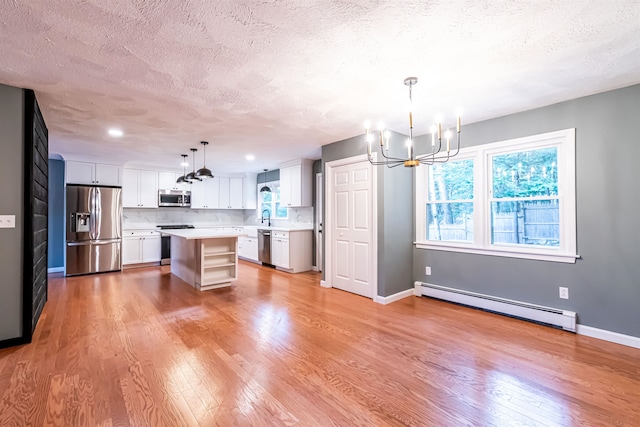 kitchen with stainless steel appliances, white cabinetry, pendant lighting, a baseboard heating unit, and a center island