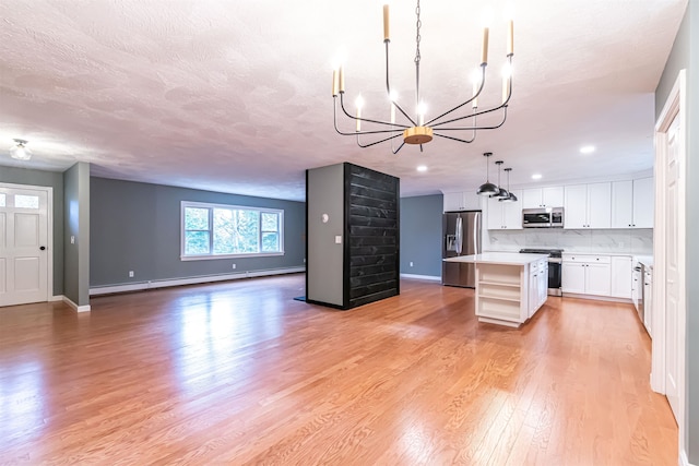 kitchen featuring light wood-type flooring, appliances with stainless steel finishes, hanging light fixtures, an inviting chandelier, and a center island