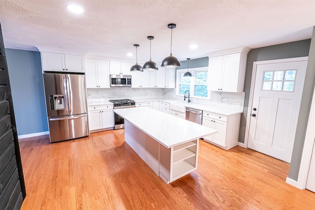 kitchen with a kitchen island, appliances with stainless steel finishes, decorative light fixtures, light hardwood / wood-style floors, and white cabinets