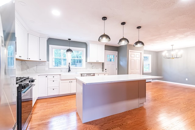 kitchen with light wood-type flooring, appliances with stainless steel finishes, sink, and a center island