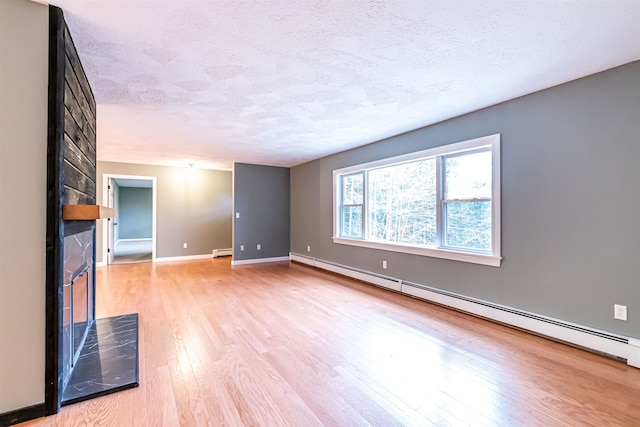 unfurnished living room with a fireplace, baseboard heating, a textured ceiling, and light wood-type flooring