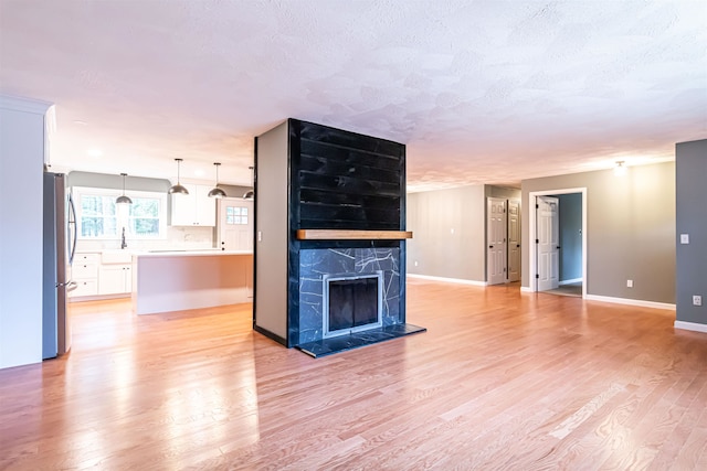 unfurnished living room featuring a premium fireplace, a textured ceiling, and light hardwood / wood-style flooring