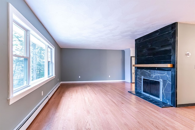 unfurnished living room featuring hardwood / wood-style flooring, a tiled fireplace, and baseboard heating