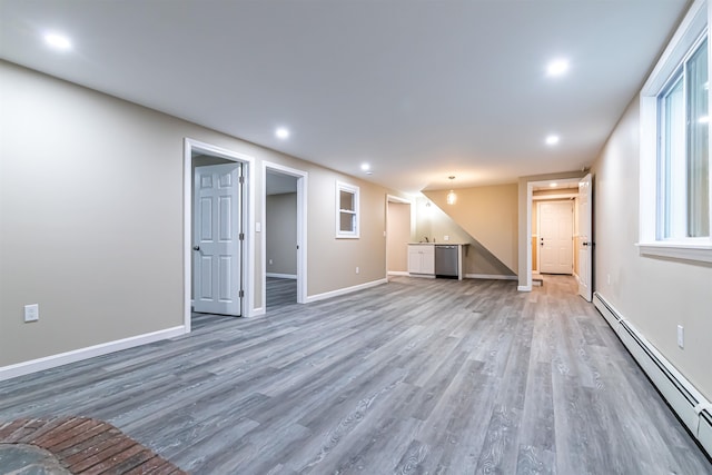 basement featuring a baseboard heating unit and hardwood / wood-style flooring