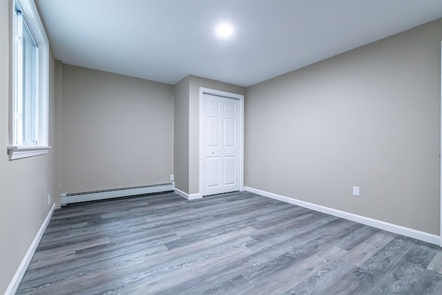 unfurnished bedroom featuring dark wood-type flooring and baseboard heating