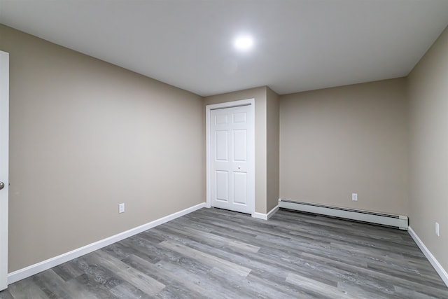 unfurnished bedroom with hardwood / wood-style floors, a baseboard radiator, and a closet