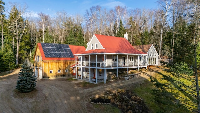 rear view of property with a garage and solar panels