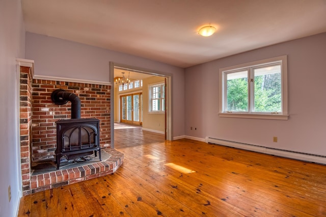 unfurnished living room with a wood stove, hardwood / wood-style floors, and a baseboard radiator