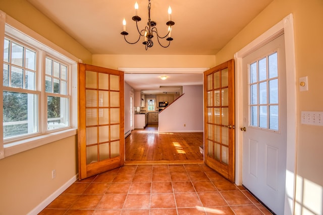 entryway with light tile patterned flooring and a chandelier