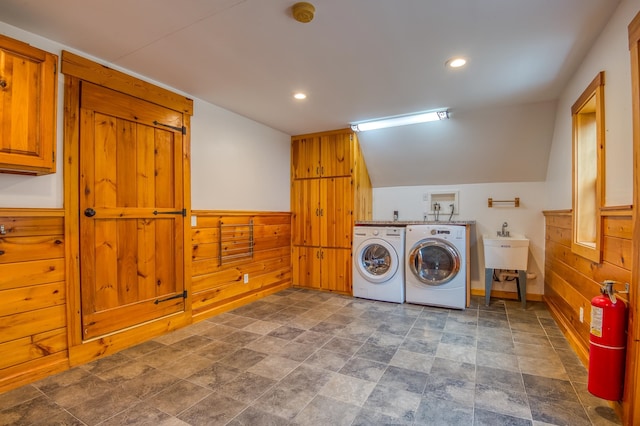 laundry room featuring sink, independent washer and dryer, wooden walls, and cabinets