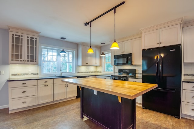 kitchen with pendant lighting, black appliances, a kitchen island, sink, and butcher block countertops