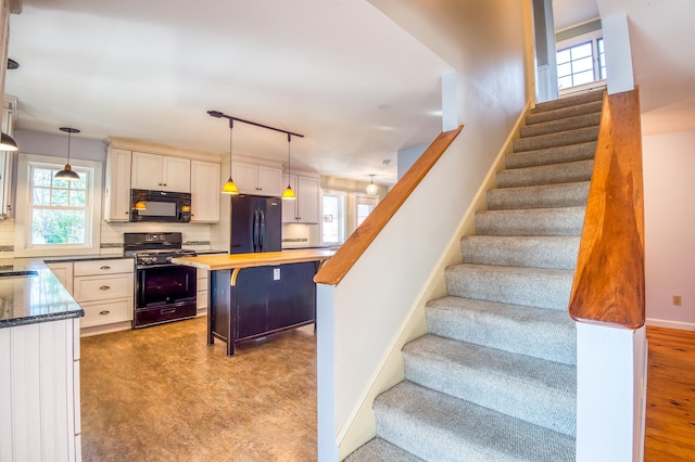 kitchen with backsplash, pendant lighting, black appliances, butcher block countertops, and a breakfast bar area