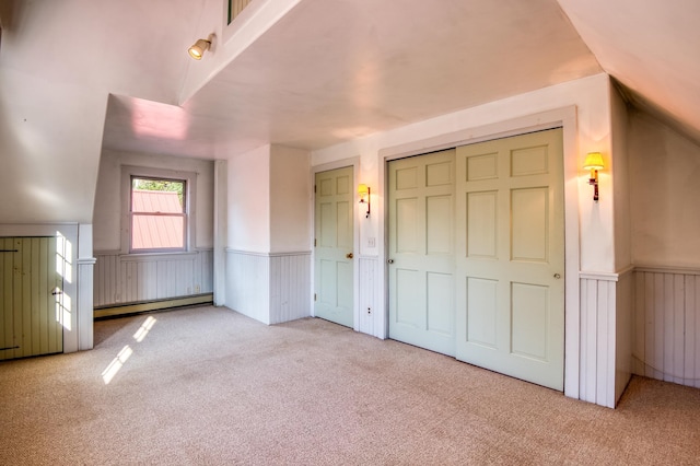 interior space featuring a baseboard heating unit, a closet, lofted ceiling, and light carpet