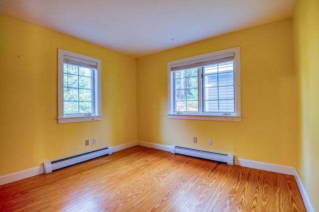 spare room featuring light hardwood / wood-style floors, baseboard heating, and plenty of natural light