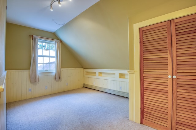 additional living space with lofted ceiling, a baseboard heating unit, and light carpet