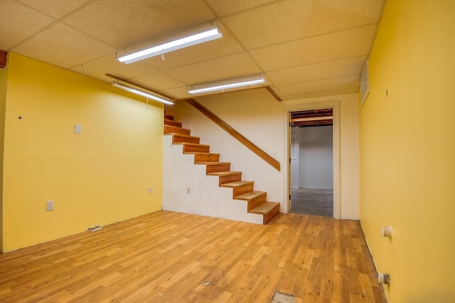 basement featuring a paneled ceiling and light hardwood / wood-style floors